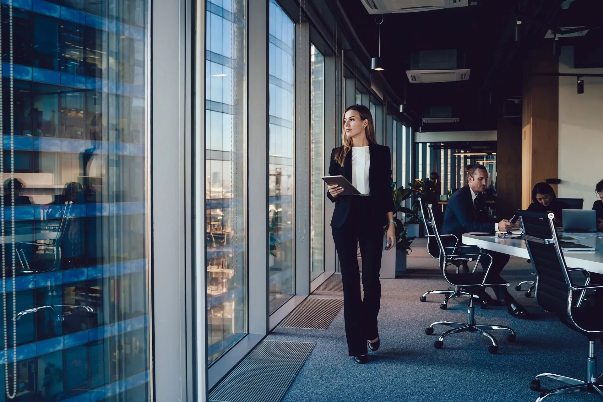 Une dirigeante traverse un couloir de bureaux vitré.